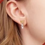Festliche Weihnachts-Glocken Ohrstecker: Detailreiche 925 Silber Ohrringe mit Gold Schleife und Perle am Ohr getragen. Weihnachtlicher Ohrschmuck.